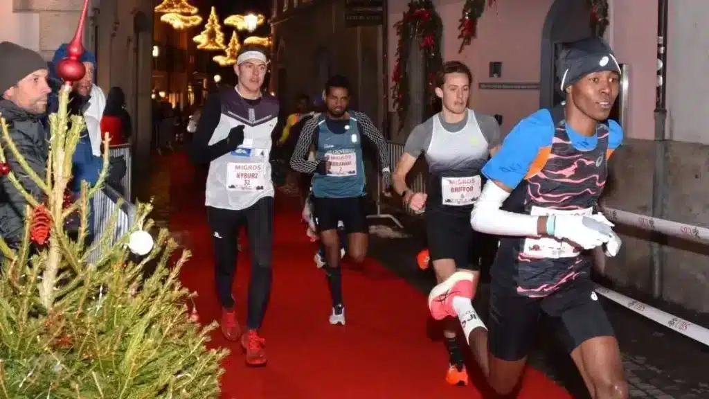 Les coureurs sont emportés par l'élan de la compétition, même en cette saison festive. Avec des décorations de Noël en toile de fond, ils incarnent la persévérance et la joie du sport, même dans le froid de l'hiver.