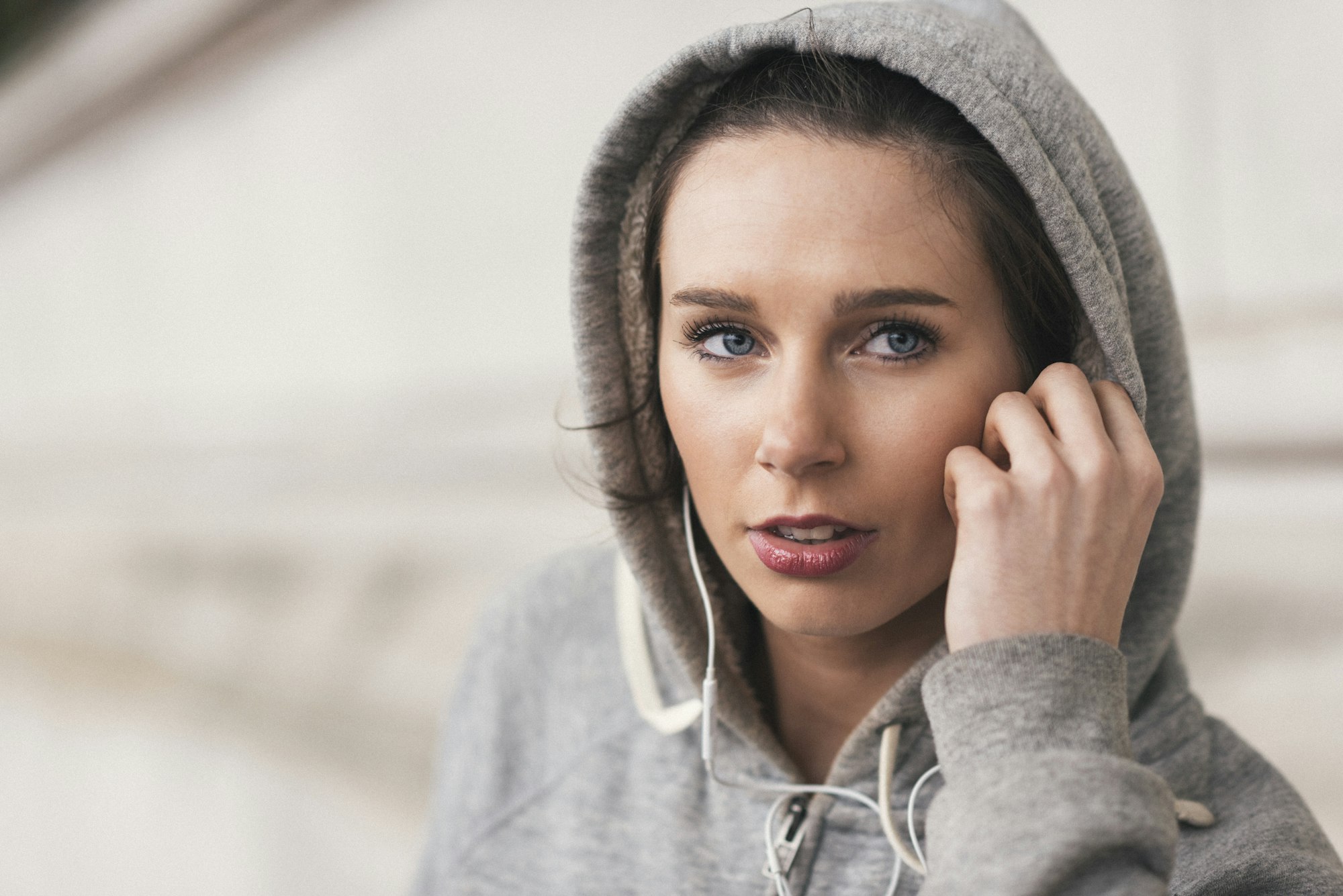 Female runner wearing grey hoody listening to music on earphones